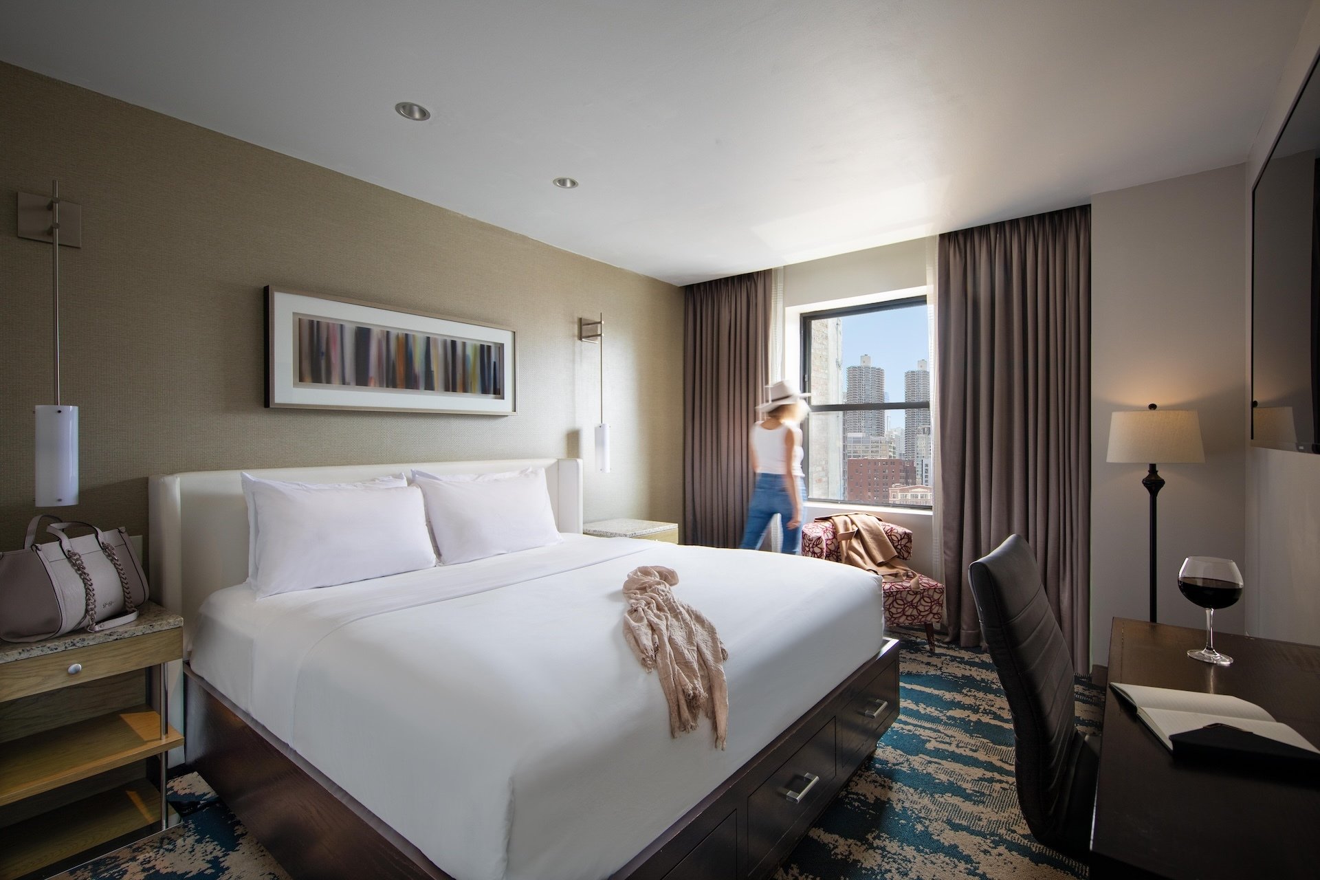 One King Room with a King Bed, Desk and a Woman Looking out the Window